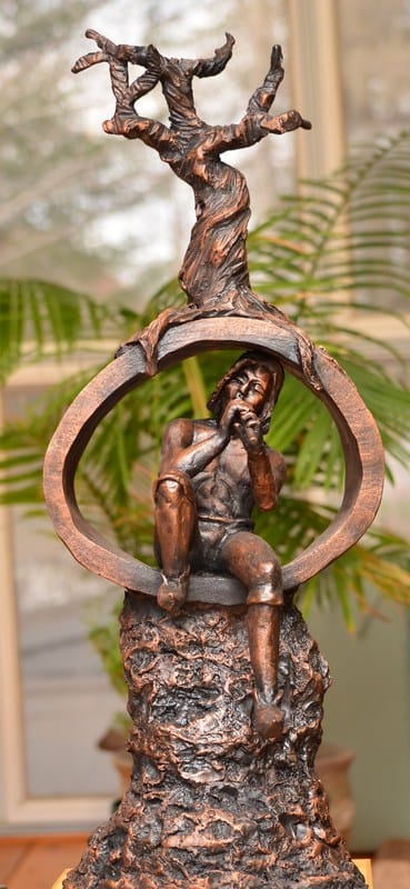 Sculpture d’argile homme qui joue de la flute avec arbre