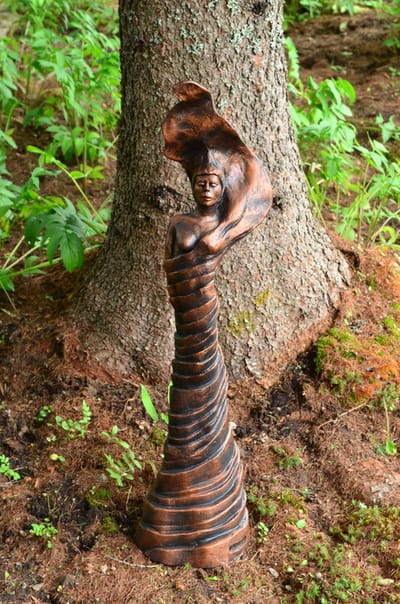sculpture d'argile d'une femme au pied d'un arbre