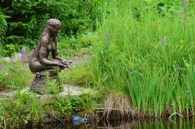 sculpture d'argile d'une femme acroupit au bord de l'eau